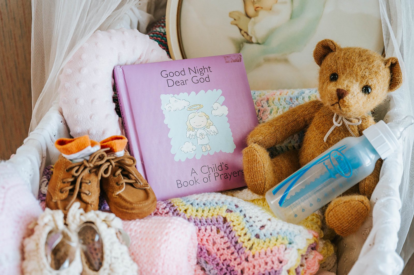 A bassinet with a children's prayer book and teddy bear